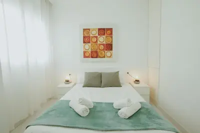 a white bedroom with a bed with two towels at Apartment Ruzafa Market 7D in Valencia
