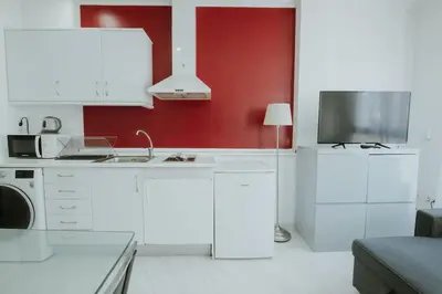 a kitchen with white cabinets and a red wall at Apartment Ruzafa Market 7D in Valencia