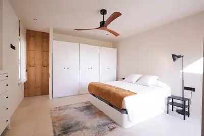 a bedroom with a white bed and a ceiling fan at Casa unifamiliar con jardín en la playa in Mareny Blau
