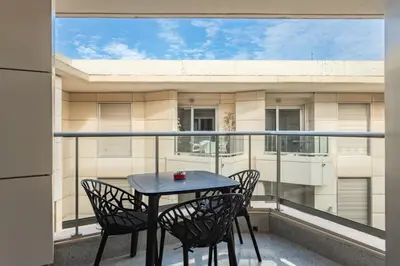 a table and chairs on a balcony with a view of a building at Valencia Beach Vibe - Oceanfront escape in Valencia