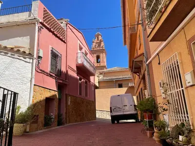 a van driving down a street with a clock tower at Gatova Sunset Retreat in Gátova