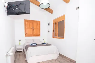 a white bedroom with a bed and a tv at En el corazón de Sagunto in Sagunto