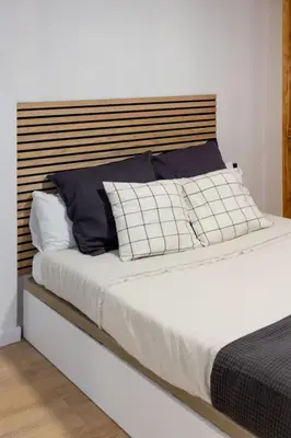 a bed with a wooden headboard and pillows on it at Valencia Leones by Concept Flats in Valencia