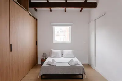 a bedroom with a bed with white sheets and a window at Burriana X - Estudio in Valencia