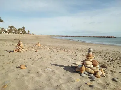 a pile of rocks sitting on a beach at Pobla de Farnals BEACH APARTMENT in Puebla de Farnals