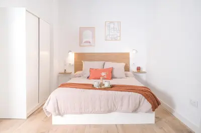 a white bedroom with a large bed with orange pillows at Suite near to Marathon - City of Arts & Sciences in Valencia
