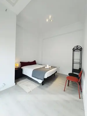 a white bedroom with a bed and a red chair at Apartment Ruzafa Market 9B in Valencia