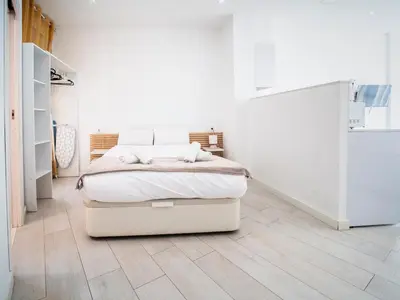a white bedroom with a bed and a wooden floor at Tu Apartamento En El Centro-Ruzafa 9D in Valencia