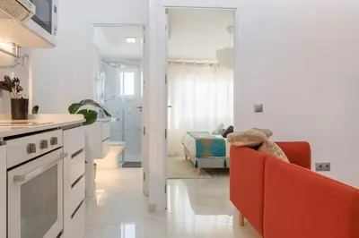 a white kitchen with a red couch and a bedroom at Top Floor 2 Bedroom Apartment with Terrace in Valencia