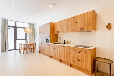 a kitchen with wooden cabinets and a table at B - Design apartment at El Grao close to the beach in Valencia
