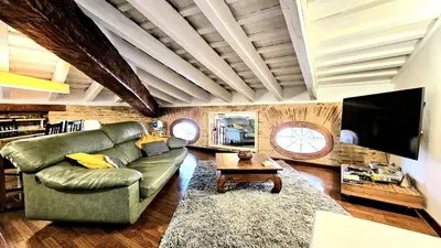 a living room with a green couch and a tv at Ático Exclusivo del Siglo XVI con Terraza Privada en el Corazón de Ciutat Vella in Valencia