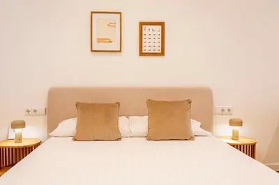 a bedroom with a large white bed with two lamps at Hridaya El Grao close to the sea in Valencia