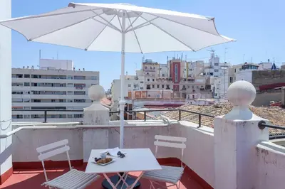 a white table and chairs with an umbrella on a roof at Penthouse apartment historical center in Valencia