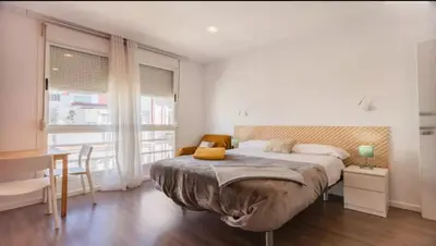 a bedroom with a large bed and a table and a desk at Tu Estudio En El Centro-Ruzafa 10C in Valencia