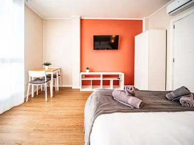 a bedroom with orange walls and a bed and a table at Estudio En El Centro-Ruzafa 10D in Valencia