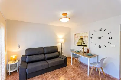 a living room with a couch and a table and a clock at A pié de playa Rincón acogedor Amanecer in Cullera