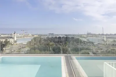 a large swimming pool with a view of a city at ApartUP Port Marina Azura in Valencia