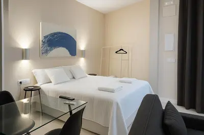 a white bedroom with a bed and a glass table at Roca Collection MSuites in Valencia