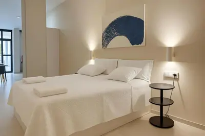 a white bedroom with a large white bed and a table at Roca Collection MSuites in Valencia