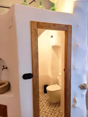 a bathroom with a toilet and a door into a room at Casa Abadía Alojamiento completo boutique cerca de Valencia in Alfarp