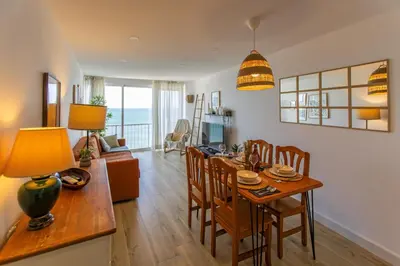 a dining room and living room with a table and chairs at Inolvidables vistas en perfecto apto frente al mar in Faro de Cullera
