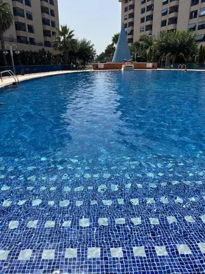 a swimming pool with blue and white tiles on it at Beachfront Family Apt in Valencia