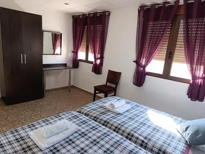 a bedroom with a bed and two chairs and a mirror at Apartamento Rural La Plaza Vieja in Viver
