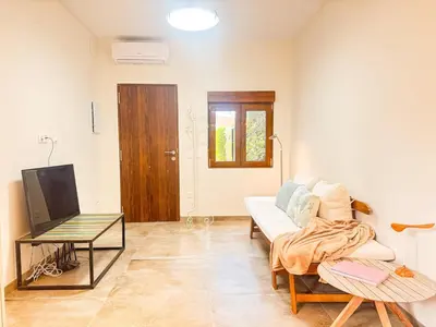 a living room with a white couch and a tv at Charming brand-new loft with garden and pool in Pla del Pou
