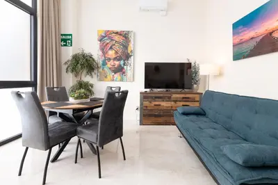 a living room with a couch and a table and a tv at Portobello Road Suites in Valencia