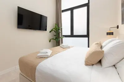 a white bedroom with a large bed with a flat screen tv at Portobello Road Suites in Valencia
