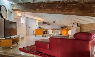 a living room with a red couch and a kitchen at Gran Ático Premium del Siglo XVI con Tres Terrazas Privadas Hasta 7 Huéspedes en Ciutat Vella in Valencia