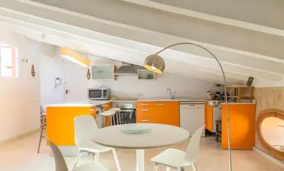a kitchen with orange cabinets and a table and chairs at Gran Ático Premium del Siglo XVI con Tres Terrazas Privadas Hasta 7 Huéspedes en Ciutat Vella in Valencia
