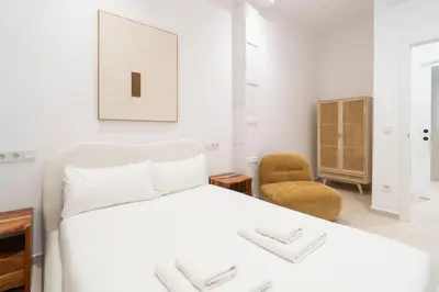 a white bedroom with a bed and a chair at VLC Host - Cubells 8 in Valencia