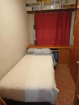 a small bed in a room with a red curtain at Alquilo habitación 24 euros por noche Super Top in Valencia