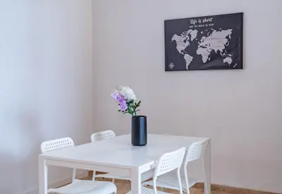 a white dining room table with white chairs and a vase with flowers at especial mediterranean room in Valencia