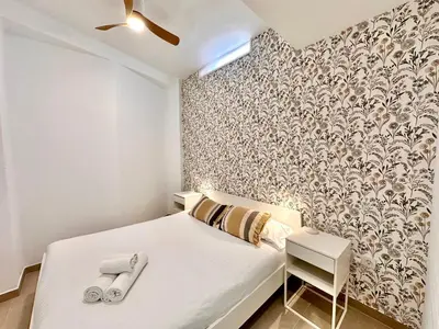 a bedroom with a white bed and a wall at Casa Rosario - Apartamento reformado en El Cabañal in Valencia