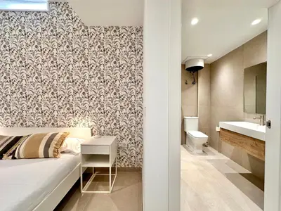 a bedroom with a bed and a bathroom with a sink at Casa Rosario - Apartamento reformado en El Cabañal in Valencia