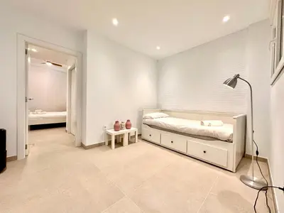 a white bedroom with a bed and a lamp at Casa Rosario - Apartamento reformado en El Cabañal in Valencia