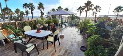 a patio with a table and chairs and palm trees at Apartamento con gran terraza frente al Mar playa Valencia in Valencia