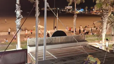 a beach at night with people walking on the beach at Apartamento con gran terraza frente al Mar playa Valencia in Valencia