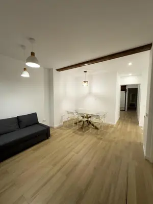 a living room with a black couch and a table at Apartamento bajo acogedor, moderno, cerca del Mar in Valencia