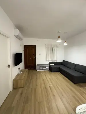 a living room with a black couch and a wooden floor at Apartamento bajo acogedor, moderno, cerca del Mar in Valencia