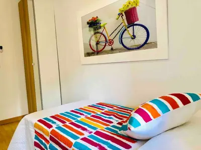 a bed with a colorful blanket and a bike on the wall at Apartamento cerca de playa y Ciudad de Ciencias in Valencia