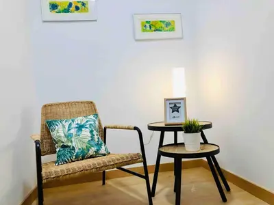 a rattan chair and a table with a pillow and a lamp at Apartamento cerca de playa y Ciudad de Ciencias in Valencia