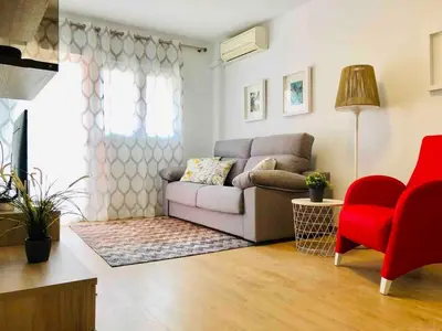 a living room with a couch and a red chair at Apartamento cerca de playa y Ciudad de Ciencias in Valencia