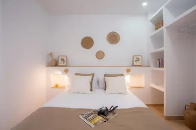 a white bedroom with a bed with a magazine on it at Casa La Pedrera in Pedralba