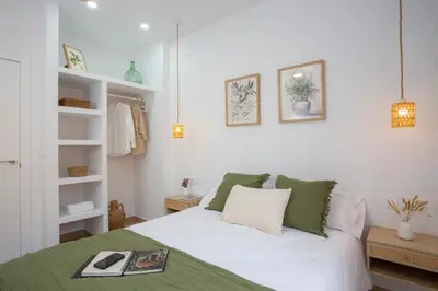 a bedroom with a bed with white sheets and green pillows at Casa La Pedrera in Pedralba