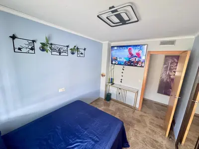 a bedroom with a blue bed and a flat screen tv at Sientete como en casa in Sedaví