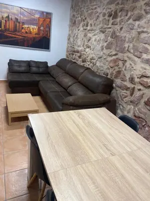 a living room with a leather couch and tables at Clau al castell apartament in Serra