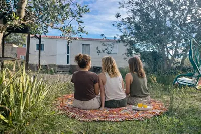 three people sitting on a blanket in the grass at A place where nothing is expected in Náquera